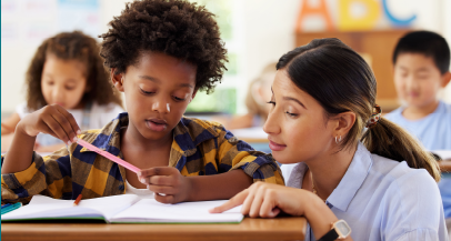 A teacher helping a student at their desk, elementary classroom setting