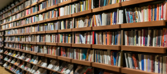 Floor to ceiling wooden bookshelves filled with colorful books. 