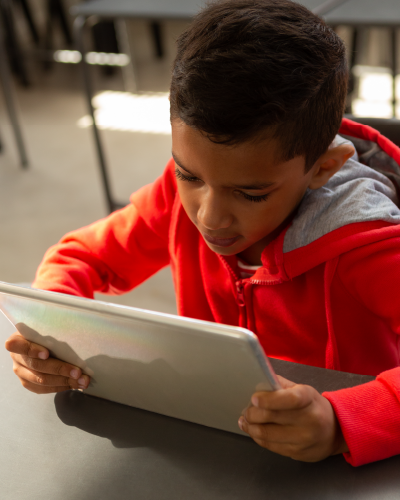 Young child reading on a tablet in a classroom setting