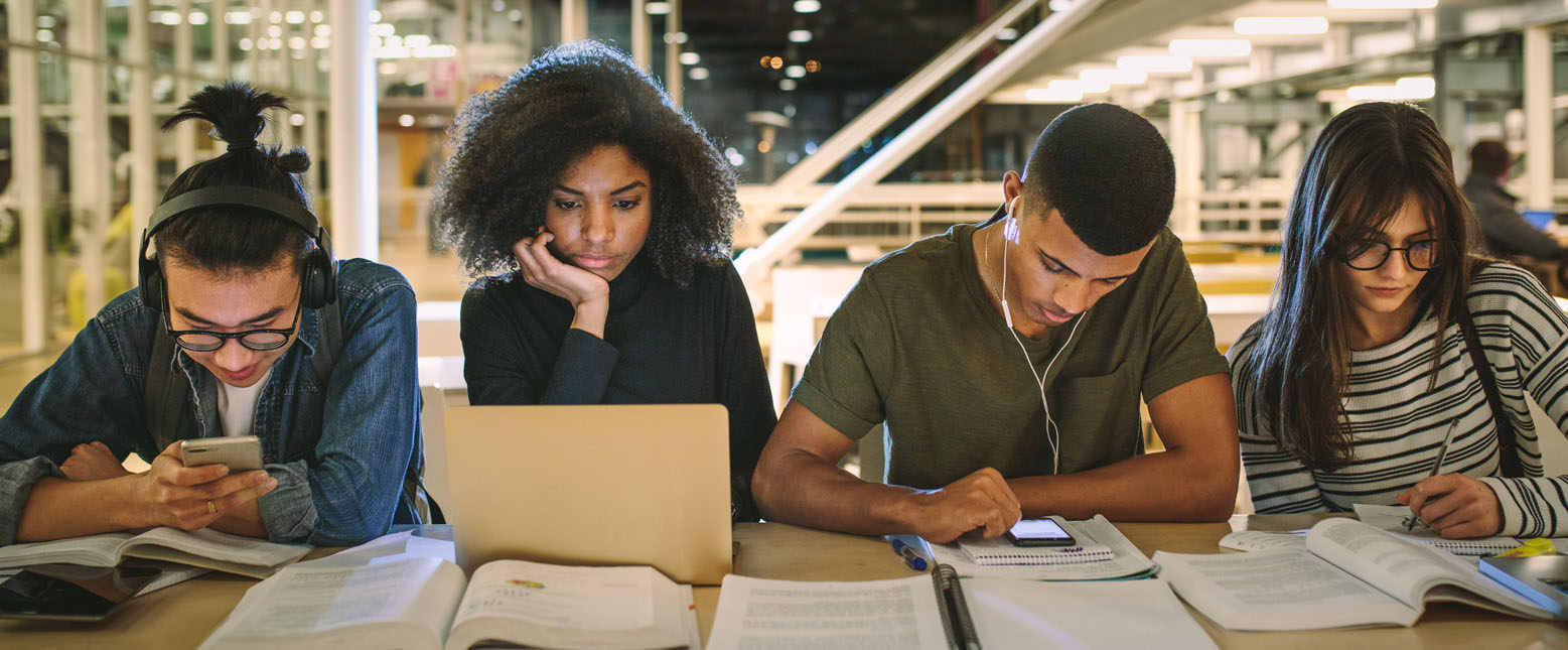 Students studying together at a library with laptops and papers on the table